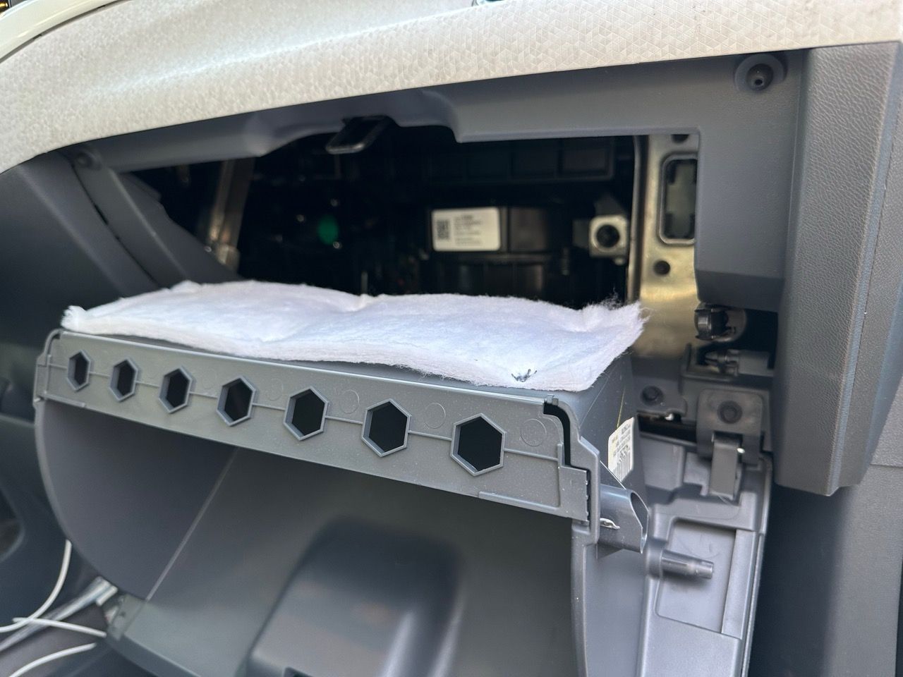 The glove box cavity. There is a white felt heat/noise isolation material on the back of the outside of the glove box.