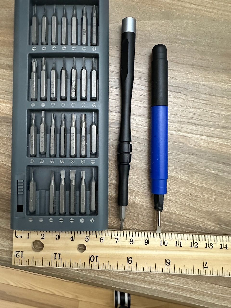 A screw driver set with two screw drivers lined up next to a ruler for scale.